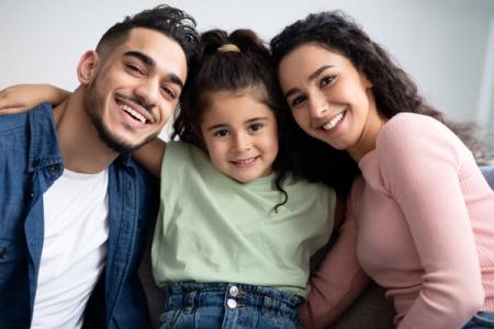 a family is posing for a picture together while sitting on a couch . a family is posing for a picture together while sitting on a couch .
