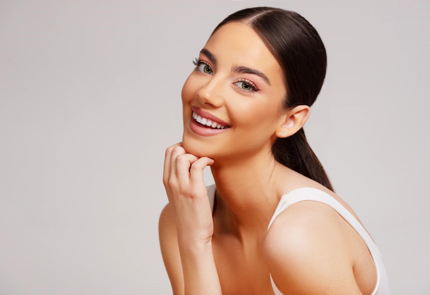 Smiling young woman with dark hair pulled back, resting her chin on her hand.
