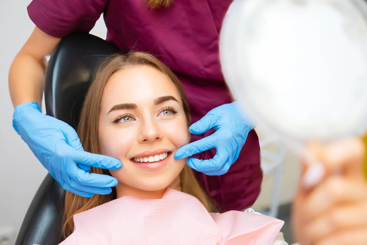 young woman smiling in the mirror at dentist office