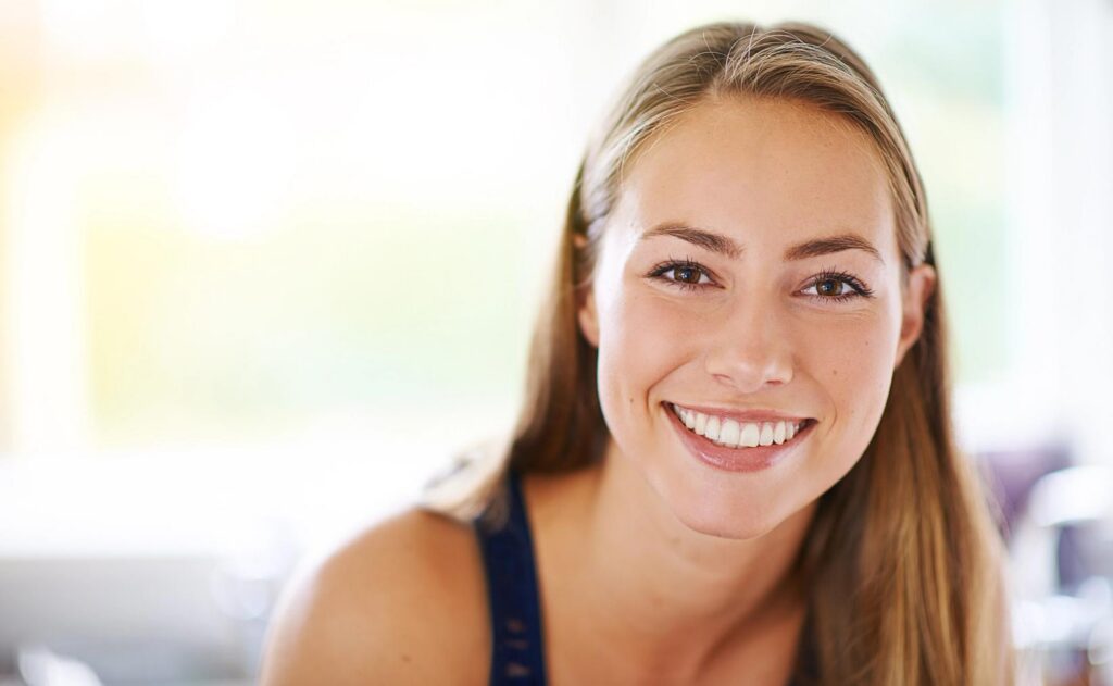 A smiling woman with long brown hair looks at the camera.