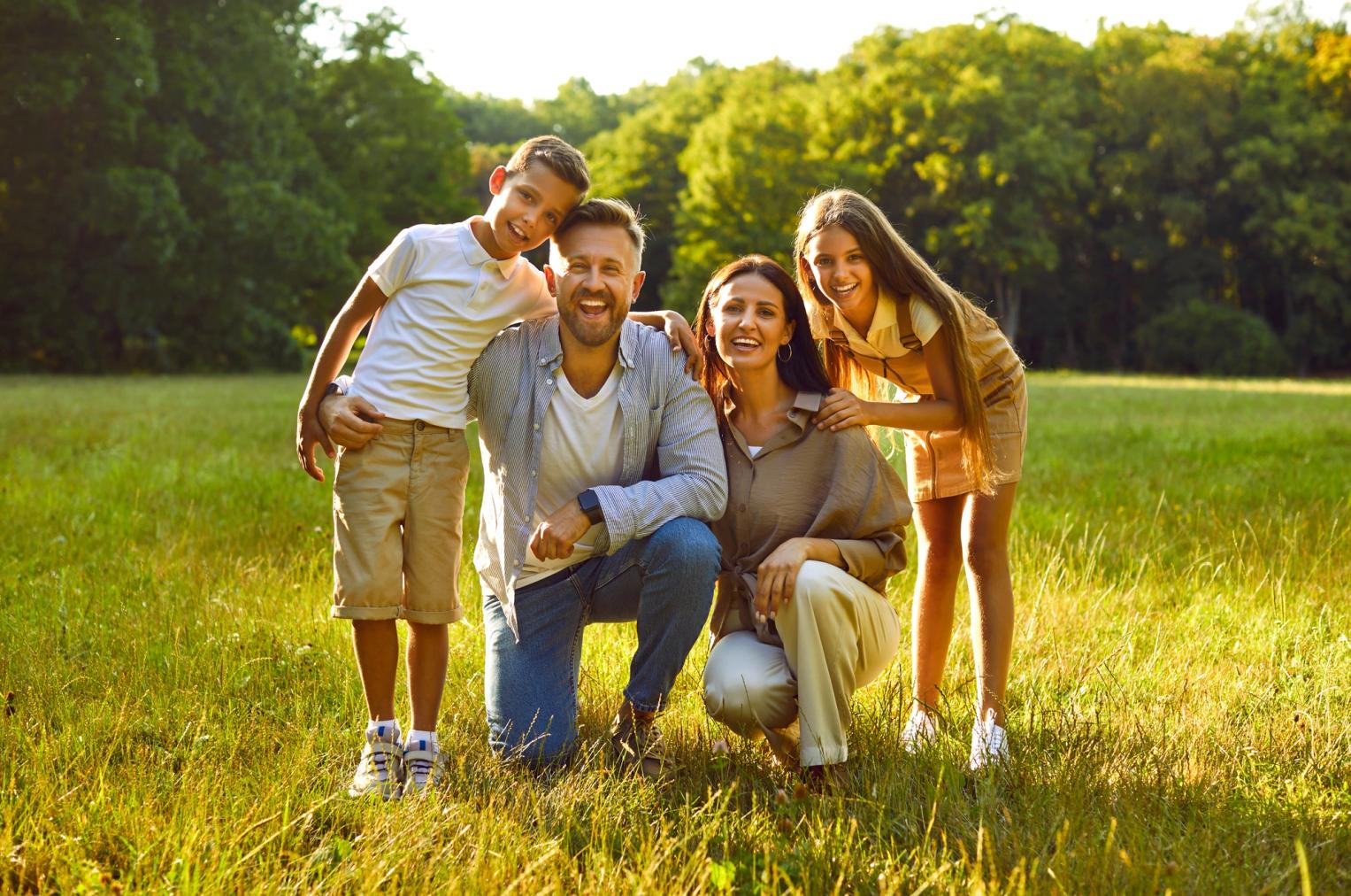 Image Alt Smiling family of four in a sunny park.