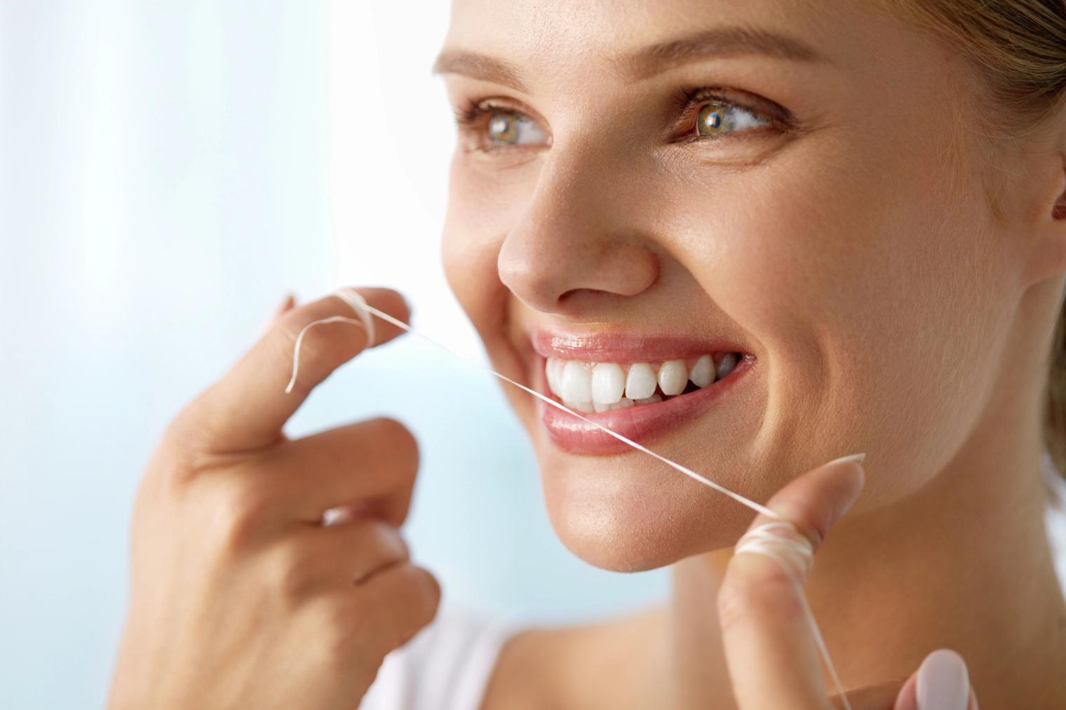 Image Alt a woman is flossing her teeth with a dental floss .