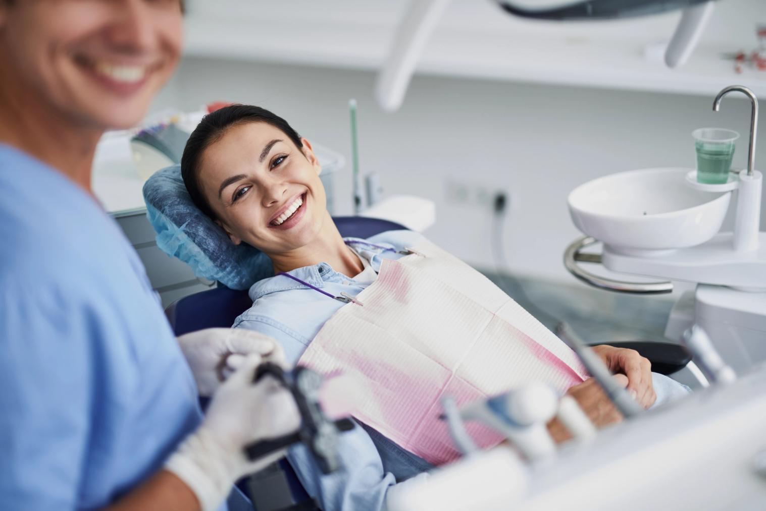 Image Alt a woman is smiling while sitting in a dental chair .