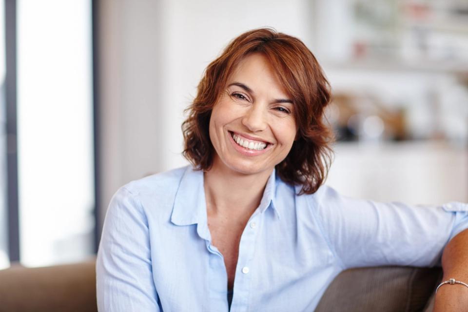 a woman is sitting on a couch smiling at the camera .