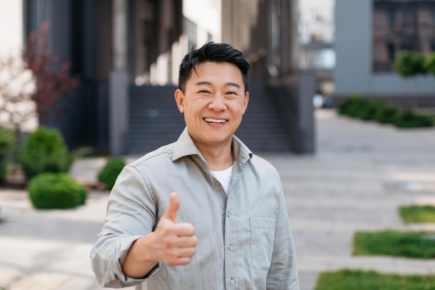 Image Alt A smiling Asian man gives a thumbs up.